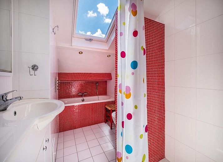 Gezellige eetruimte in vakantiehuis Guillaume in Koksijde, West-Vlaanderen, met kleurrijke stoelen en uitzicht op de lichte woonkamer.