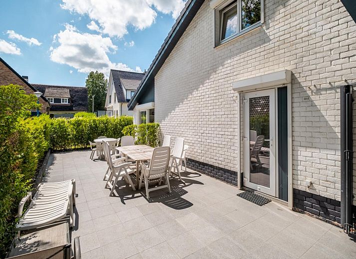 Gezellige eetruimte in vakantiehuis Guillaume in Koksijde, West-Vlaanderen, met kleurrijke stoelen en uitzicht op de lichte woonkamer.