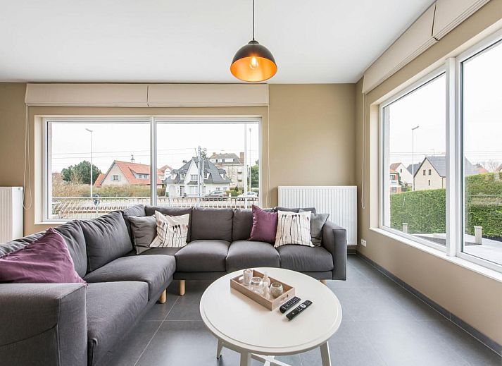 Stylish living room of vacation home La Vachequirit in Koksijde, West Flanders with comfortable seating area and large windows for plenty of light.