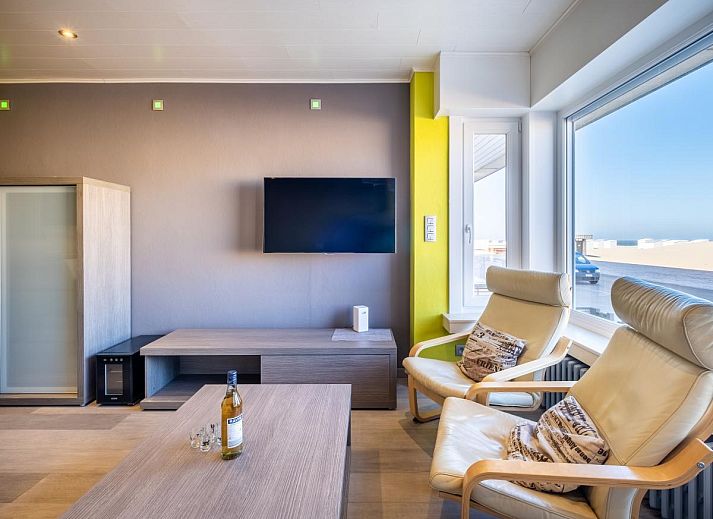 Stijlvol ingerichte woonkamer van vakantiehuis Zeezicht GV in Koksijde, West-Vlaanderen met uitzicht op de duinen.