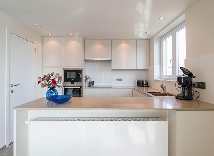 Lichte woonkamer van Bon Accueil tweede vakantiehuis in Koksijde, West-Vlaanderen, met moderne inrichting en uitzicht op het terras.