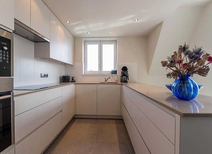 Moderne keuken in vakantiehuis Bon Accueil tweede in Koksijde, West-Vlaanderen, Belgie, met strakke witte kasten en veel natuurlijk licht.