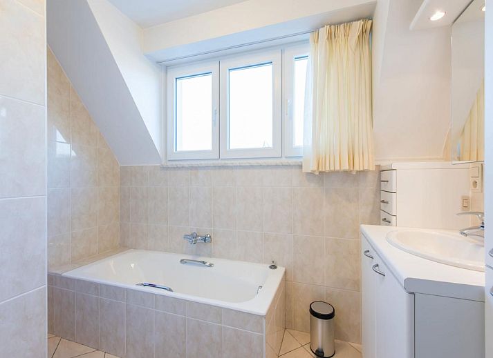 Gezellige woonkamer in vakantiehuis Mallory, Koksijde, met comfortabele banken en veel natuurlijk licht, ideaal voor ontspanning in West-Vlaanderen.