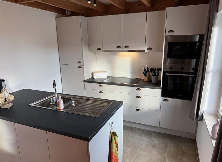 Gezellige eetkamer en keuken in vakantiehuis Westhinder II H23, Koksijde, West-Vlaanderen, met moderne inrichting en uitzicht op de tuin.