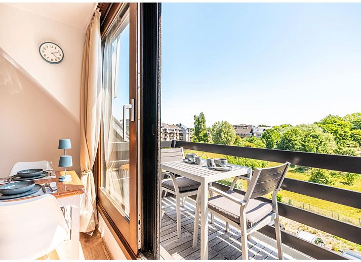 Lichte woonkamer van Ardoise des dunes vakantiehuis in Koksijde, West-Vlaanderen, met uitzicht op groene omgeving.