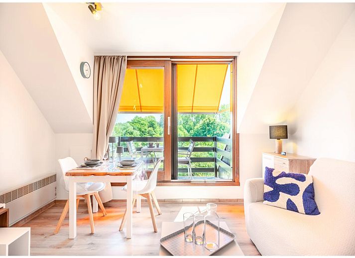 Lichte woonkamer van Ardoise des dunes vakantiehuis in Koksijde, West-Vlaanderen, met uitzicht op groene omgeving.