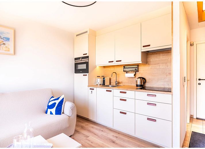 Lichte woonkamer van Ardoise des dunes vakantiehuis in Koksijde, West-Vlaanderen, met uitzicht op groene omgeving.