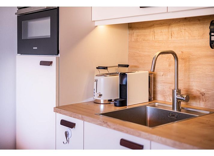 Lichte woonkamer van Ardoise des dunes vakantiehuis in Koksijde, met uitzicht op groen vanaf het balkon, West-Vlaanderen, Belgie.