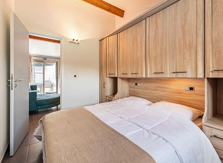 Gemuetliches Wohnzimmer des Ferienhauses Westhinder II H19 in Koksijde, Westflandern, mit bequemem Sofa und moderner Kueche.