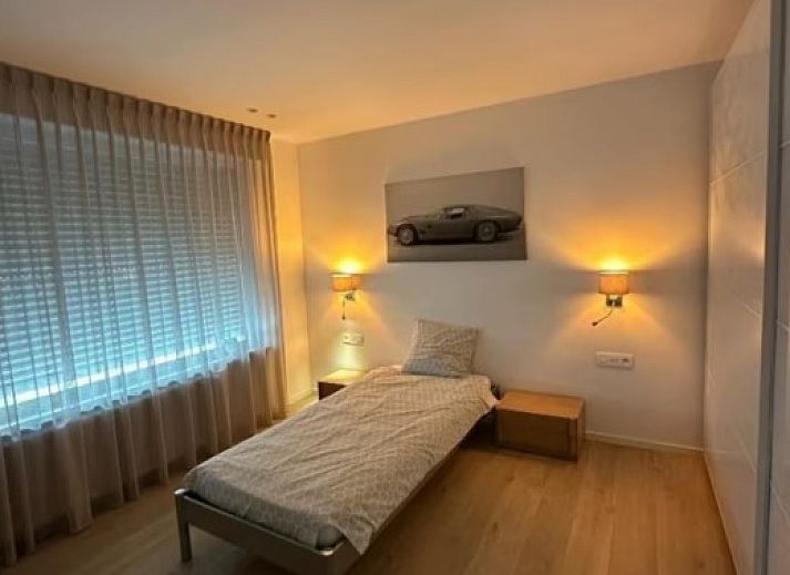 Blick auf den historischen Turm von Flat Memling in Sint-Andries, Westflandern, Belgien, umgeben von baumbestandenen Daechern.