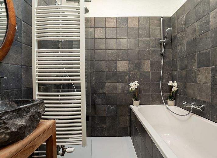 Stijlvolle badkamer van Vakantiehuis Gigi in Vlissegem, West-Vlaanderen met moderne douche en bad, ideaal voor een rustiek verblijf.