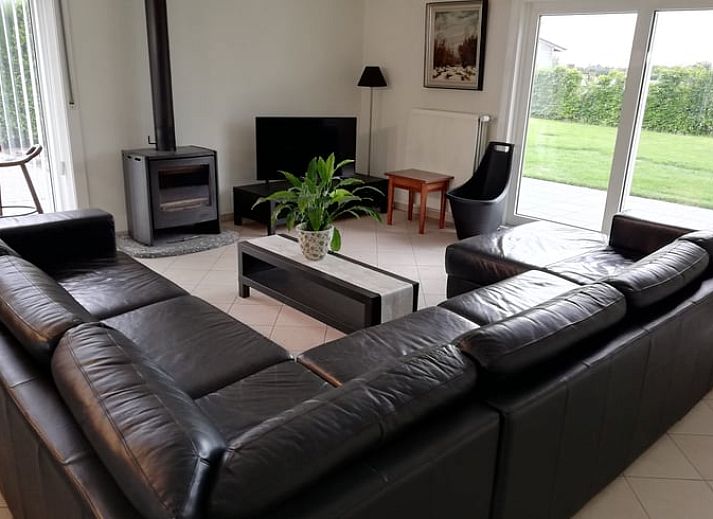 Rustige patio van vakantiehuis in Ingooigem, omgeven door groene heggen en planten, ideaal voor ontspanning in West-Vlaanderen.