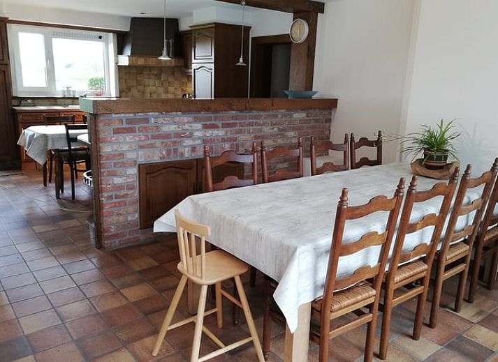 Rustige patio van vakantiehuis in Ingooigem, omgeven door groene heggen en planten, ideaal voor ontspanning in West-Vlaanderen.