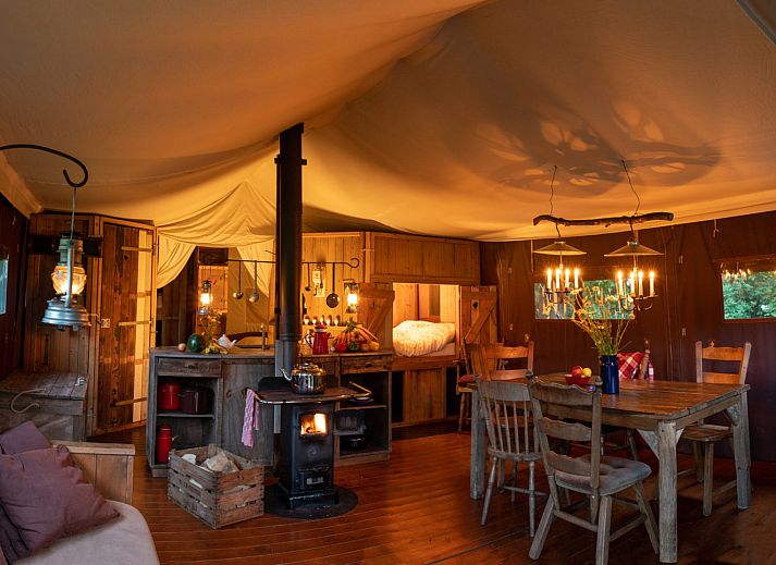 Cozy indoor area of Tent House with hot private shower in Torhout, West Flanders. Luxury glamping with wood stove and dining area.