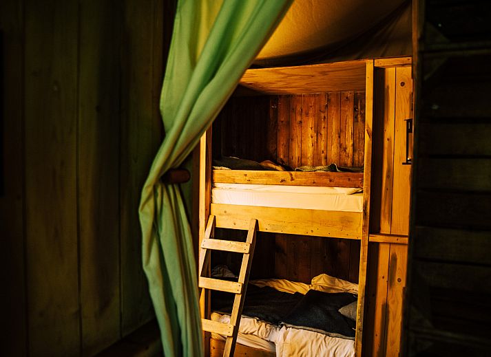 Cozy indoor area of Tent House with hot private shower in Torhout, West Flanders. Luxury glamping with wood stove and dining area.