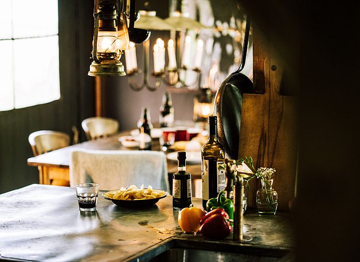 Cozy indoor area of Tent House with hot private shower in Torhout, West Flanders. Luxury glamping with wood stove and dining area.