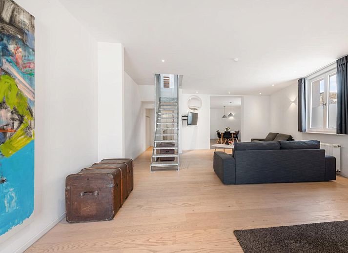 Stilvolles Wohnzimmer des Ferienhauses "De Loft" in Veurne, Westflandern, mit moderner Einrichtung und einer grosszuegigen Sitzecke.