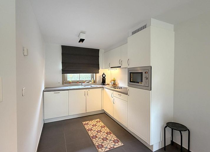 Gemuetliches Wohnzimmer im Ferienhaus Home Sweet Home, De Panne, mit moderner Einrichtung und Blick auf den gruenen Garten in Westflandern, Belgien.