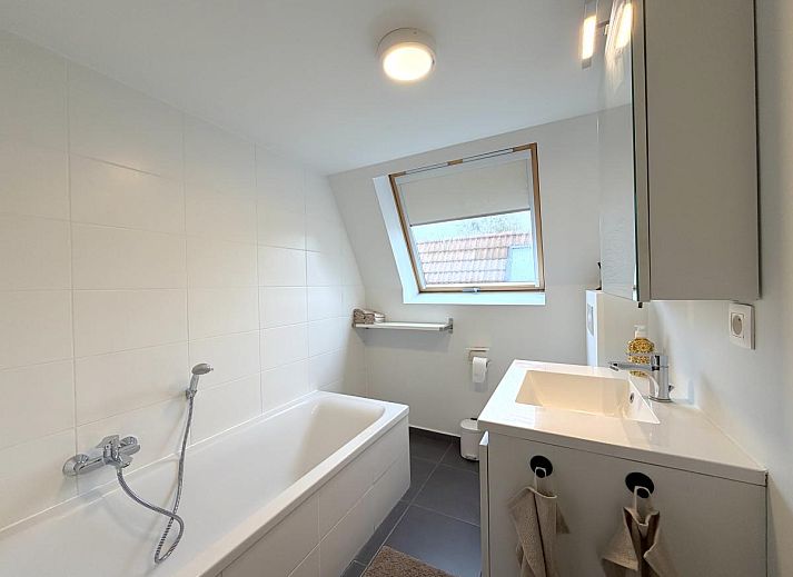 Gemuetliches Wohnzimmer im Ferienhaus Home Sweet Home, De Panne, mit moderner Einrichtung und Blick auf den gruenen Garten in Westflandern, Belgien.