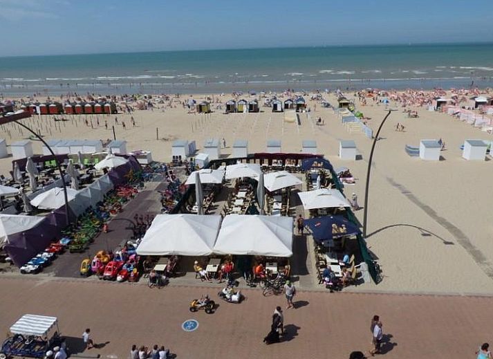 Cozy living room of Ramses studio in De Panne, Belgian coast, with red sofa and balcony with sea view.