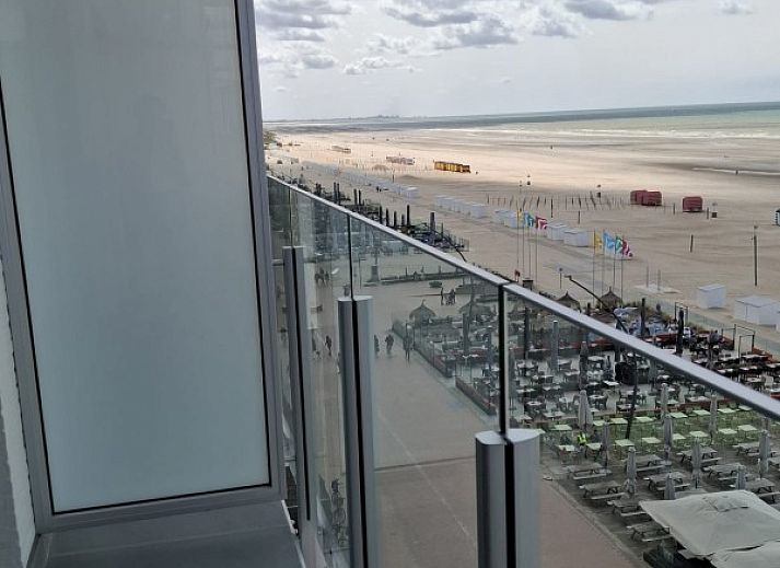 Cozy living room of Ramses studio in De Panne, Belgian coast, with red sofa and balcony with sea view.