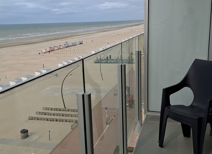 Cozy living room of Ramses studio in De Panne, Belgian coast, with red sofa and balcony with sea view.