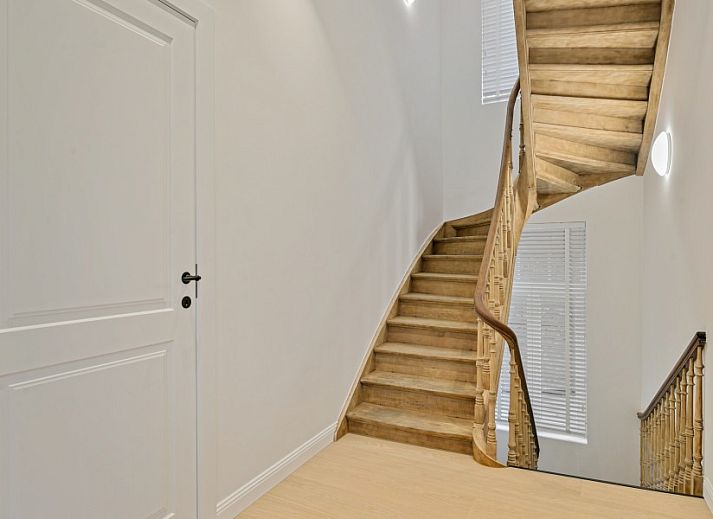 Diele von Maison Perron, Ferienhaus De Panne, Westflandern mit Holztreppe und altem Stuhl.