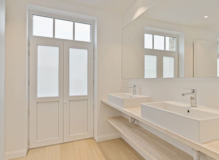 Gemuetliches Wohnzimmer von Maison Perron, Ferienhaus De Panne, Westflandern mit bequemem Sofa und Kunst an der Wand.