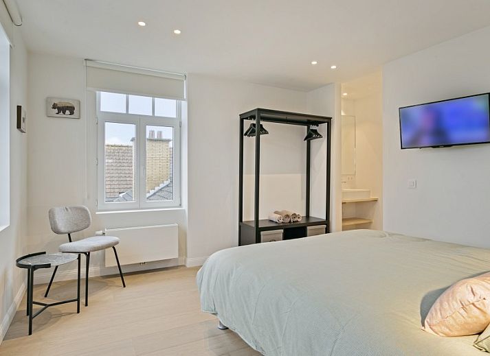 Gemuetliches Wohnzimmer von Maison Perron, Ferienhaus De Panne, Westflandern mit bequemem Sofa und Kunst an der Wand.