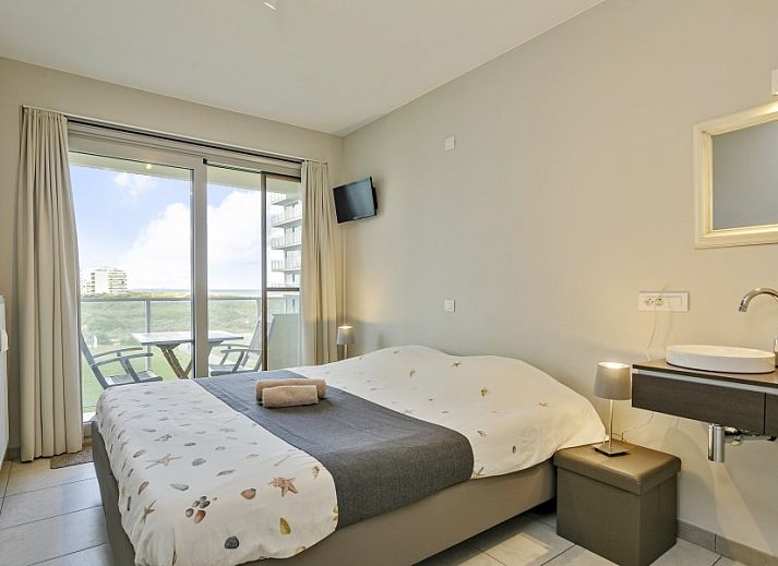 Balcony of Flat Fleur apartment in De Panne, West Flanders overlooking modern building and sea.
