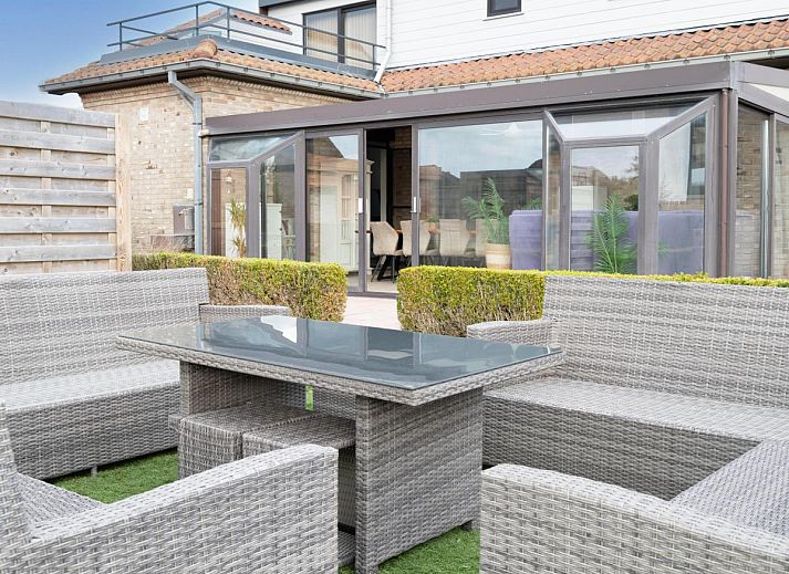 Vorderansicht des Ferienhauses De Golfbreker in Middelkerke, umgeben von einem Zaun und einer Steinauffahrt in Westflandern.