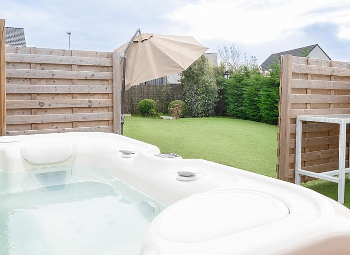 Vorderansicht des Ferienhauses De Golfbreker in Middelkerke, umgeben von einem Zaun und einer Steinauffahrt in Westflandern.