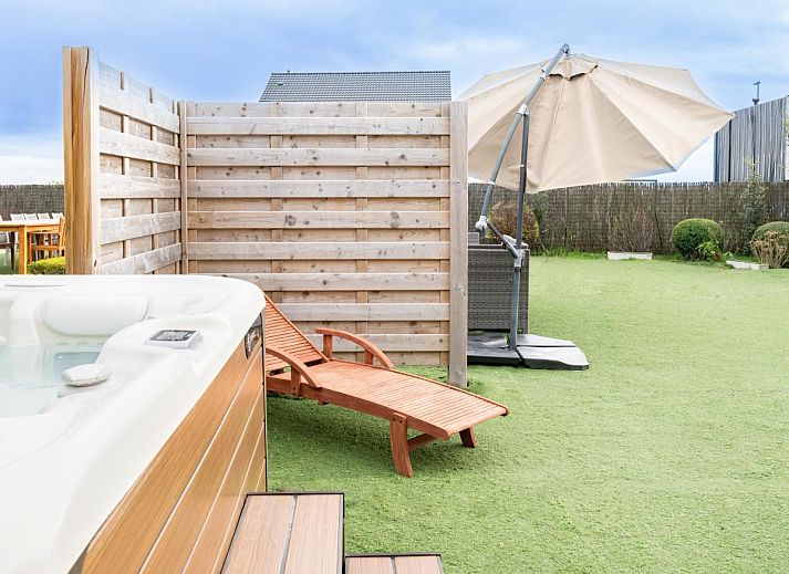 Vorderansicht des Ferienhauses De Golfbreker in Middelkerke, umgeben von einem Zaun und einer Steinauffahrt in Westflandern.