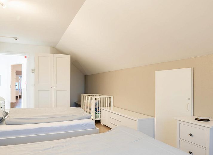 Vorderansicht des Ferienhauses De Golfbreker in Middelkerke, umgeben von einem Zaun und einer Steinauffahrt in Westflandern.