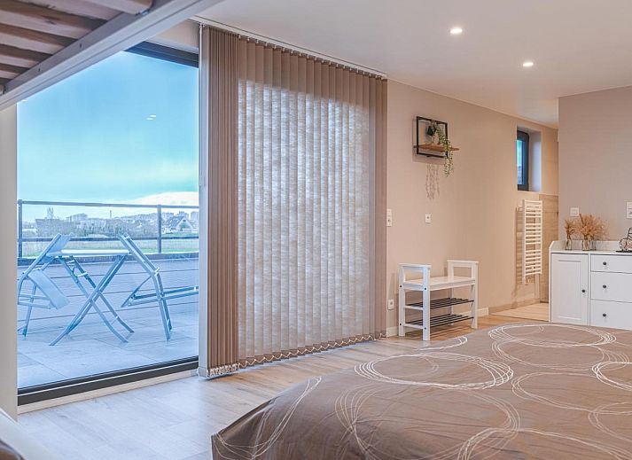 Geraeumige Terrasse von De Golfbreker in Middelkerke mit Holztisch und Stuehlen, ideal fuer Mahlzeiten im Freien in Westflandern.