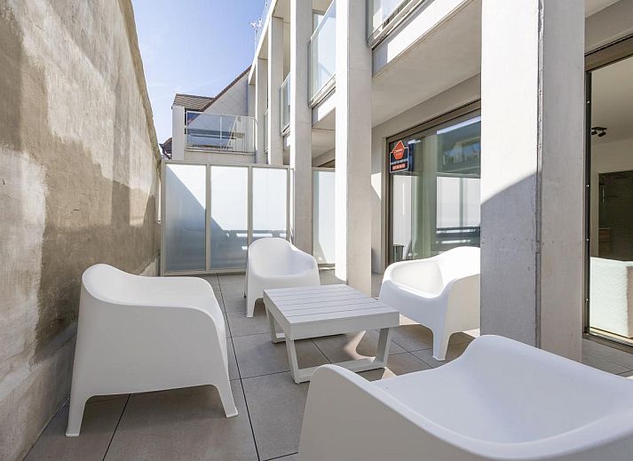 Moderne Veranda des Ferienhauses Omnia 7 - 0103 + Park. 5 in Middelkerke, Westflandern, Belgien, mit weissen Stuehlen und einem kleinen Tisch.