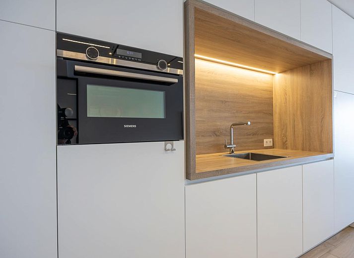 Moderne Kueche im Ferienhaus "Exception - 0801 + Park. 39" in Middelkerke, Westflandern, mit eleganter Holzausstattung und stilvoller Essecke.