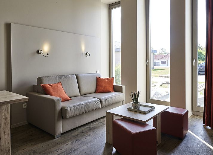 Gemuetliche Sitzecke im Familienstudio fuer 2 Erwachsene und 3 Kinder in Middelkerke, mit Blick auf den Garten und den Picknicktisch in Westflandern.