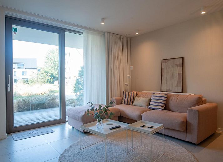 Veranda van West Bay vakantiehuis in Westende, West-Vlaanderen, met comfortabele zitplaatsen en groene omgeving.