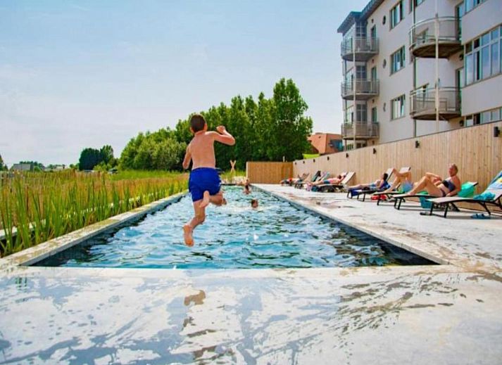 Veranda van West Bay vakantiehuis in Westende, West-Vlaanderen, met comfortabele zitplaatsen en groene omgeving.