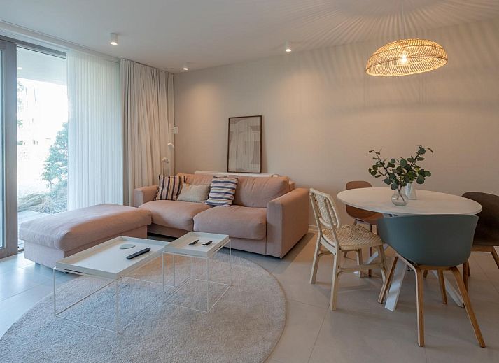 Gezellige woonkamer van West Bay vakantiehuis in Westende, West-Vlaanderen met comfortabele bank en uitzicht op de tuin.