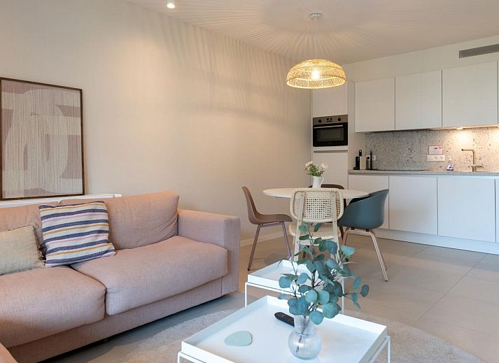 Gezellige woonkamer van West Bay vakantiehuis in Westende, West-Vlaanderen met comfortabele bank en uitzicht op de tuin.