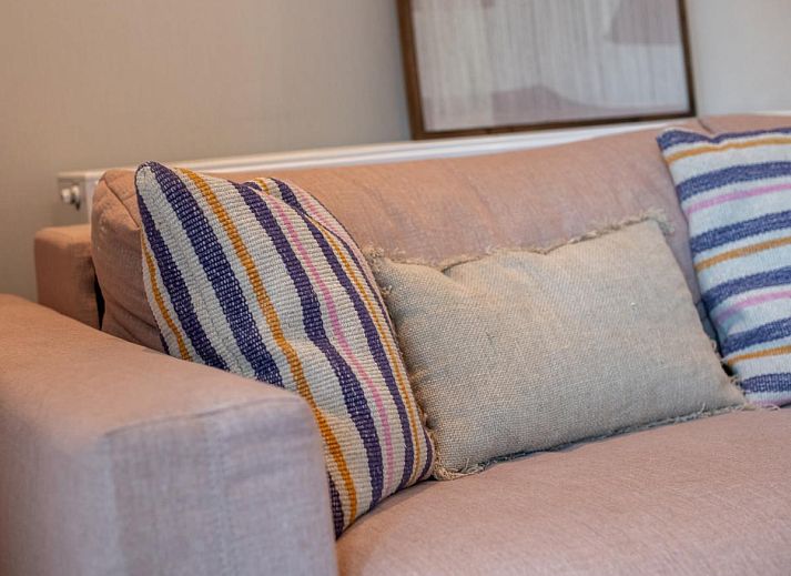 Gezellige woonkamer van West Bay vakantiehuis in Westende, West-Vlaanderen met comfortabele bank en uitzicht op de tuin.