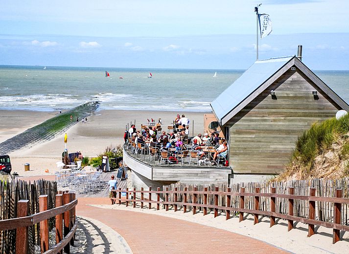 Zonnig terras van Appartement Cocoon in Bredene, West-Vlaanderen, Belgie, met houten tuinmeubilair en uitzicht op de moderne omgeving.