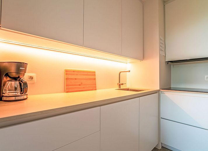 Helles Wohnzimmer der Ferienwohnung Residentie Astrid in Bredene, Westflandern, mit Blick auf den Garten und moderner Moeblierung.