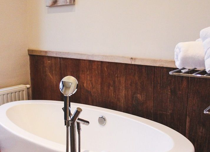 Cozy living room in Maracci vacation home Pervijze with wooden stairs and comfortable seating.