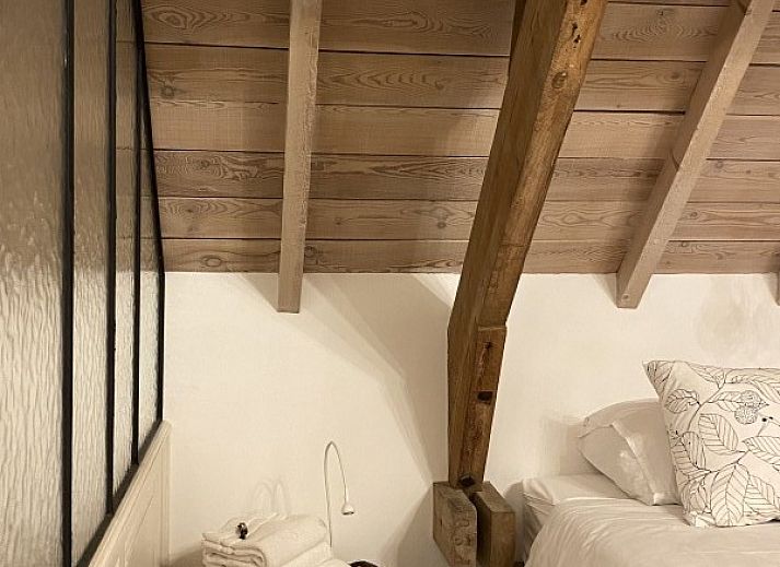 Comfortable bedroom in Maracci vacation home Pervijze with rustic wooden bench.