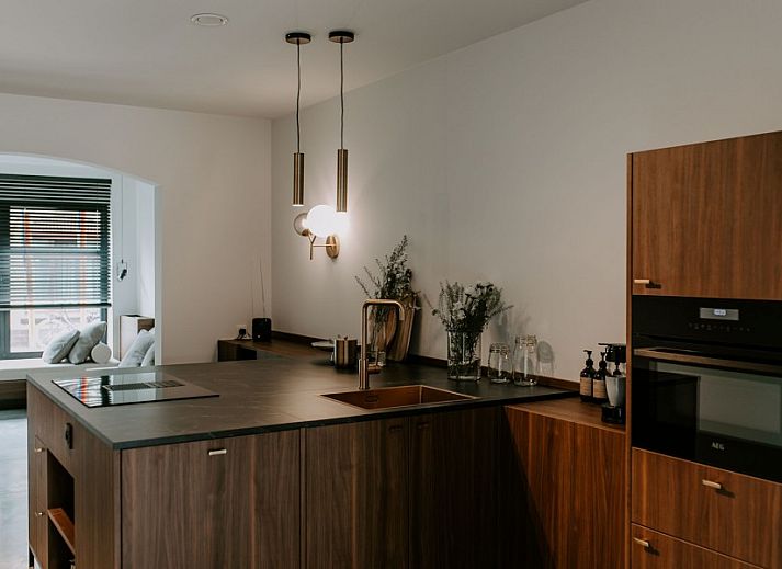 Stijlvolle hal van Jolie Logie, vakantiehuis in Nieuwpoort, West-Vlaanderen, met houten bank en moderne verlichting.