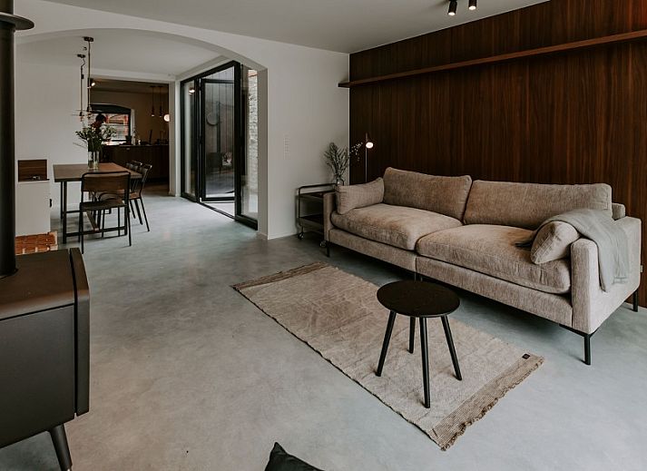 Stijlvolle hal van Jolie Logie, vakantiehuis in Nieuwpoort, West-Vlaanderen, met houten bank en moderne verlichting.