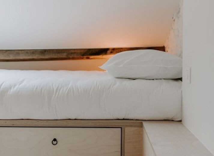 Sfeervolle verlichting naast bed in Jolie Logie, vakantiehuis in Nieuwpoort, West-Vlaanderen, met houten details.